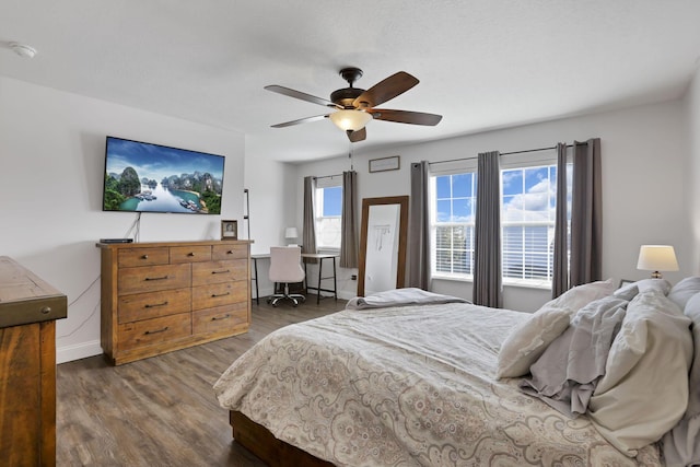 bedroom with ceiling fan, dark wood-style flooring, and baseboards