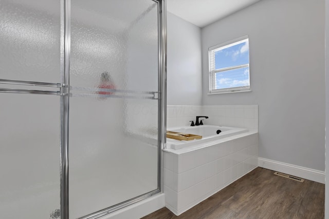 full bath featuring a garden tub, visible vents, a shower stall, wood finished floors, and baseboards