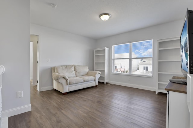 living area featuring baseboards and dark wood-style flooring