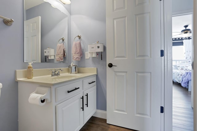 ensuite bathroom featuring a ceiling fan, vanity, ensuite bath, wood finished floors, and baseboards