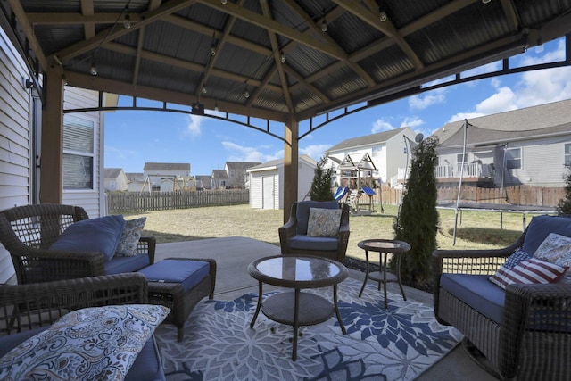 view of patio / terrace with a trampoline, an outbuilding, a playground, a shed, and a fenced backyard