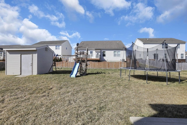 view of yard with an outbuilding, a trampoline, fence, a shed, and a playground