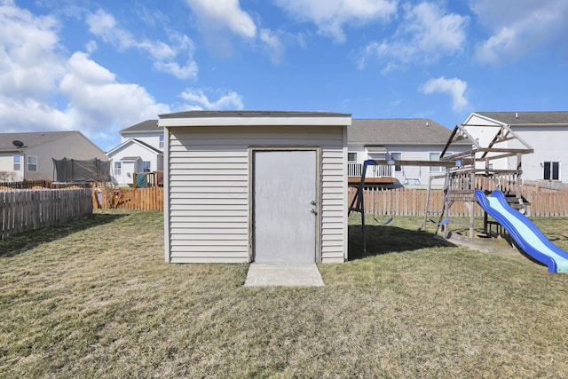 view of shed with a trampoline, a playground, and a fenced backyard