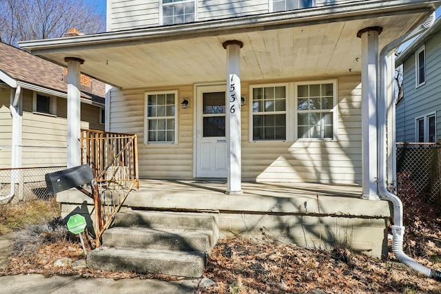 doorway to property featuring a porch and fence