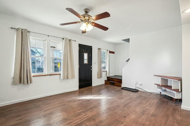 foyer entrance featuring a ceiling fan, stairs, baseboards, and wood finished floors