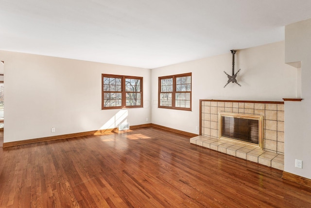 unfurnished living room with visible vents, baseboards, wood finished floors, and a tile fireplace