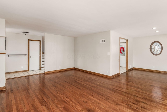 empty room featuring recessed lighting, wood finished floors, visible vents, baseboards, and stairway