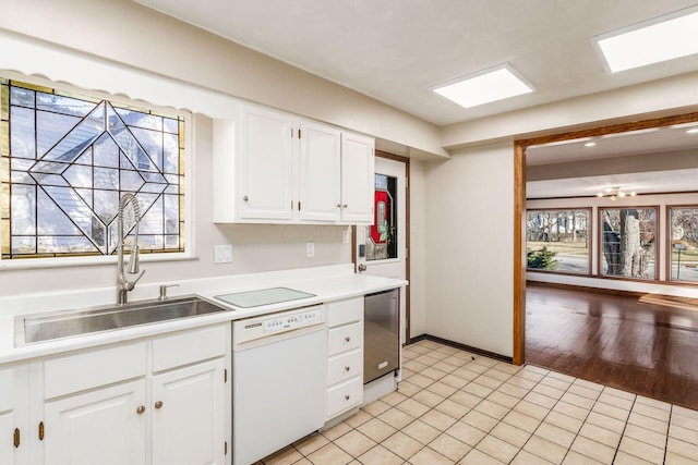 kitchen with a sink, white cabinets, light countertops, and dishwasher