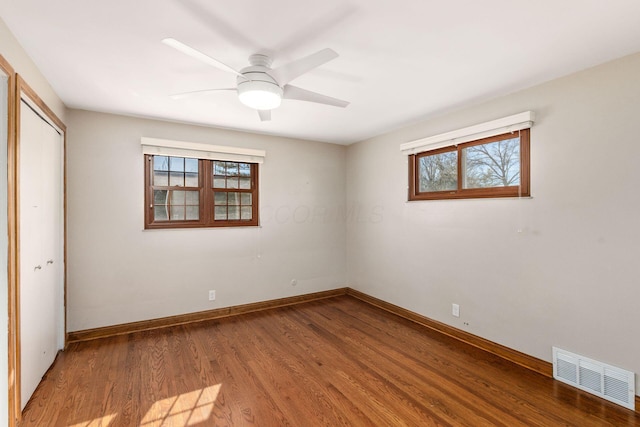 unfurnished bedroom featuring a closet, visible vents, multiple windows, and wood finished floors