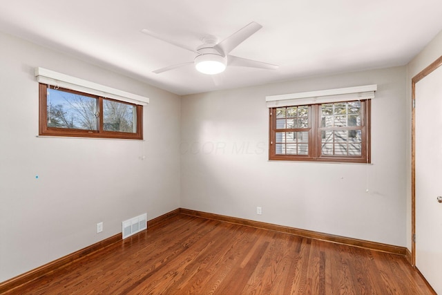 unfurnished room featuring a ceiling fan, visible vents, baseboards, and wood finished floors