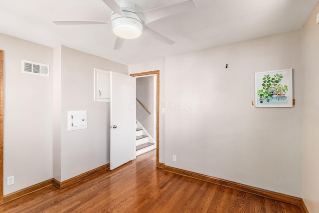 spare room with baseboards, visible vents, ceiling fan, and wood finished floors