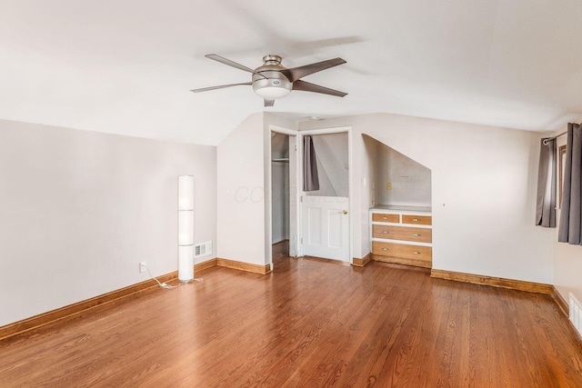 bonus room with baseboards, visible vents, vaulted ceiling, and wood finished floors