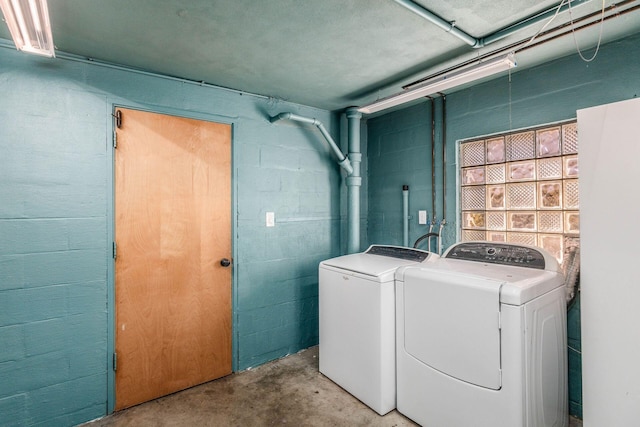 laundry area with separate washer and dryer and concrete block wall