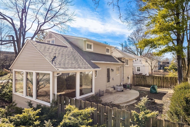 rear view of property with a shingled roof, a patio, and fence