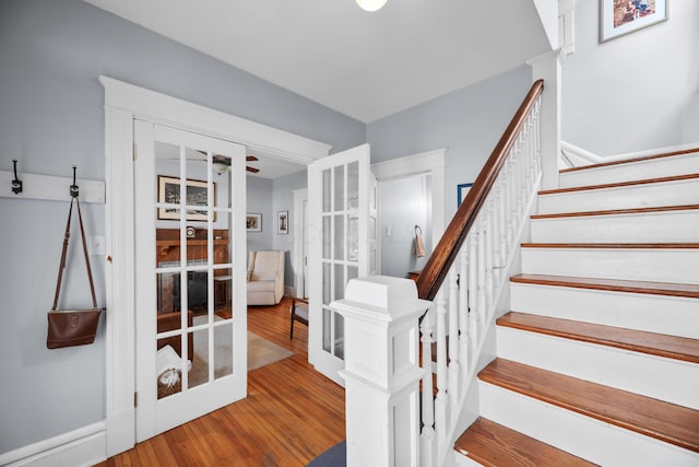 staircase with french doors, a ceiling fan, and wood finished floors