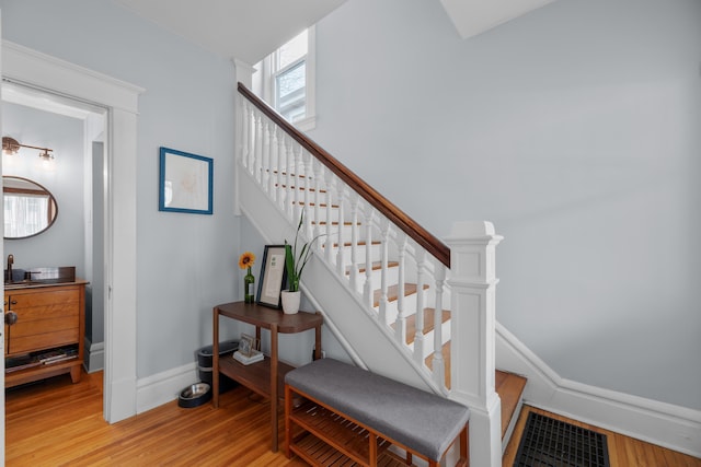 stairway with visible vents, wood finished floors, and baseboards