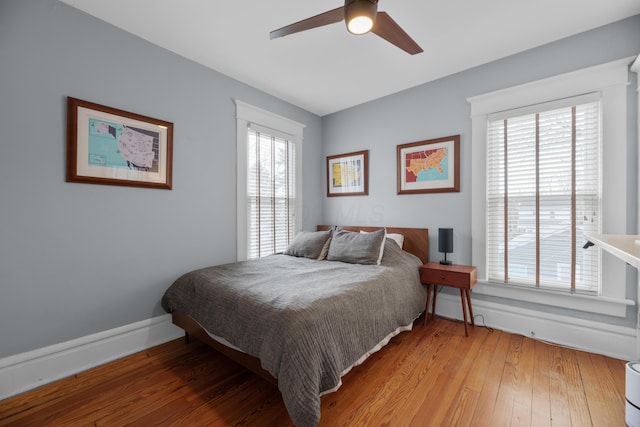 bedroom with baseboards, multiple windows, and light wood finished floors