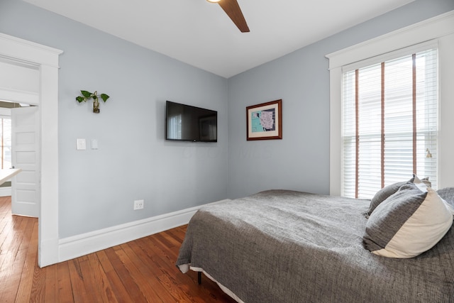 bedroom with baseboards, multiple windows, ceiling fan, and hardwood / wood-style flooring