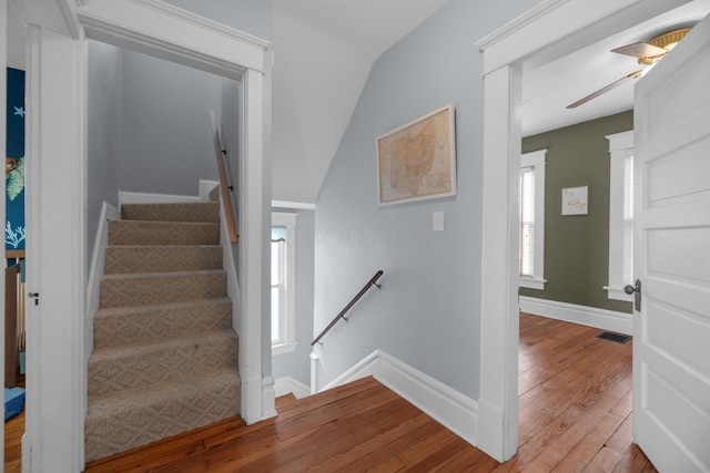 stairs with visible vents, a ceiling fan, baseboards, and wood-type flooring