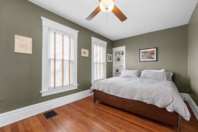 bedroom featuring visible vents, a ceiling fan, baseboards, and hardwood / wood-style floors