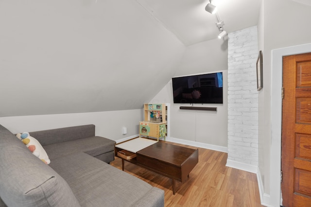 living room with lofted ceiling, rail lighting, baseboards, and light wood finished floors