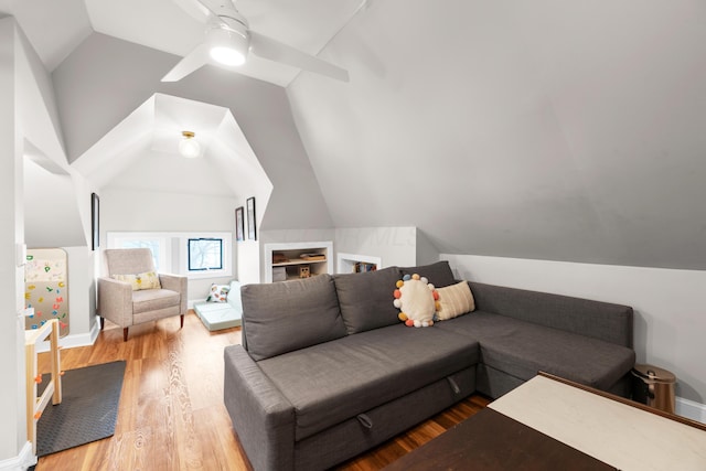 living area featuring lofted ceiling, wood finished floors, baseboards, and ceiling fan