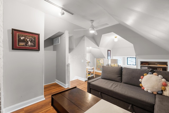 living room with visible vents, track lighting, baseboards, vaulted ceiling, and light wood-style flooring