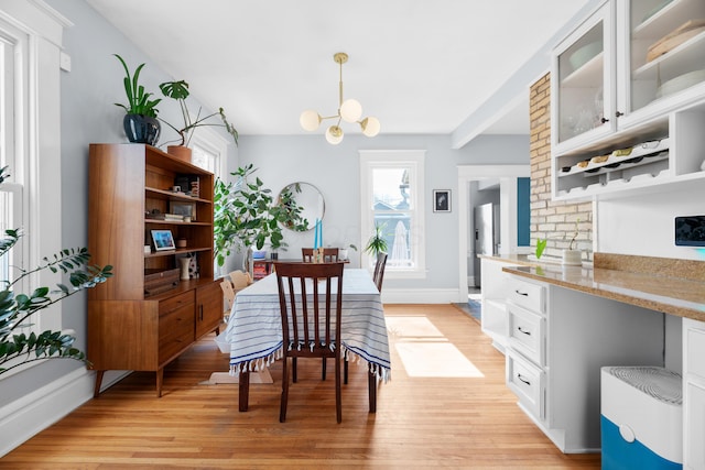 dining space featuring a chandelier, baseboards, and light wood-style floors