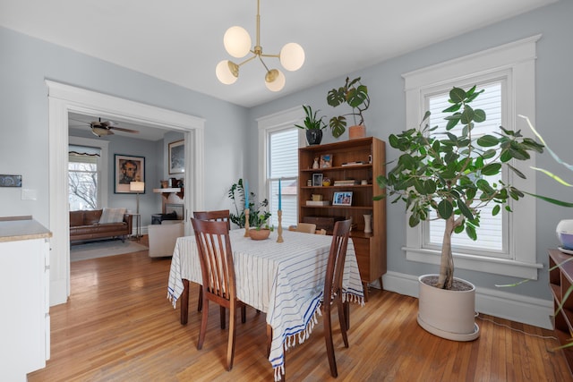 dining space featuring plenty of natural light, ceiling fan with notable chandelier, baseboards, and light wood-style floors