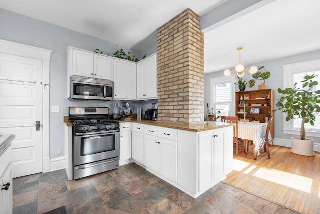 kitchen featuring baseboards, plenty of natural light, appliances with stainless steel finishes, and white cabinets