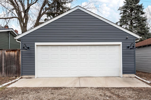 garage featuring driveway and fence