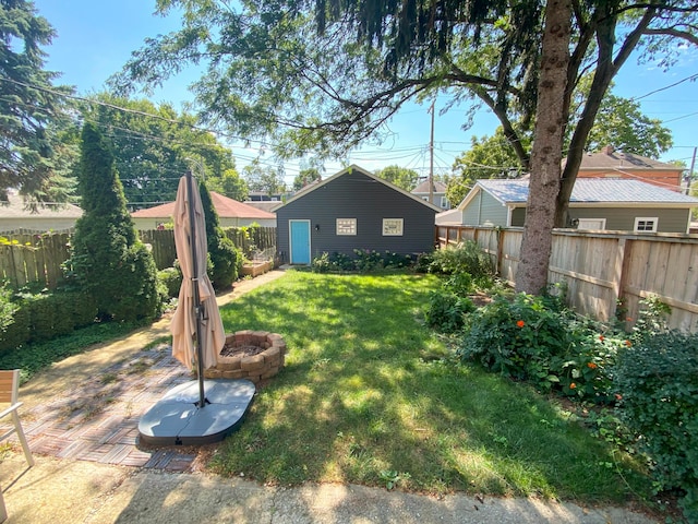 view of yard with an outdoor structure, a fire pit, and a fenced backyard