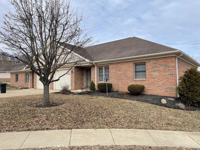 ranch-style home featuring a garage, brick siding, driveway, and roof with shingles