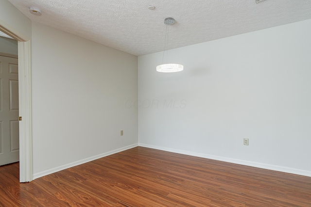 empty room featuring baseboards, dark wood finished floors, and a textured ceiling