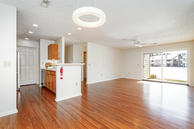 unfurnished living room with baseboards, visible vents, a ceiling fan, dark wood-style flooring, and recessed lighting