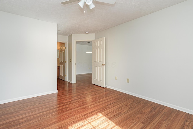 empty room featuring a textured ceiling, ceiling fan, wood finished floors, and baseboards