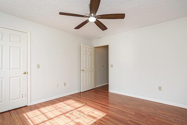 spare room featuring ceiling fan, a textured ceiling, baseboards, and wood finished floors