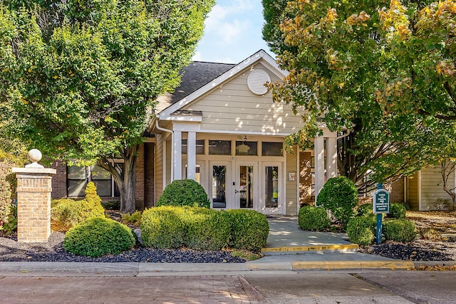 view of front of property featuring french doors, a shingled roof, and brick siding