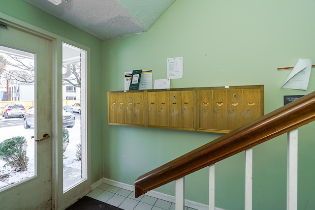 entryway featuring a textured ceiling, light tile patterned flooring, mail area, and baseboards