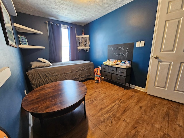 bedroom with baseboards, a textured ceiling, and wood finished floors