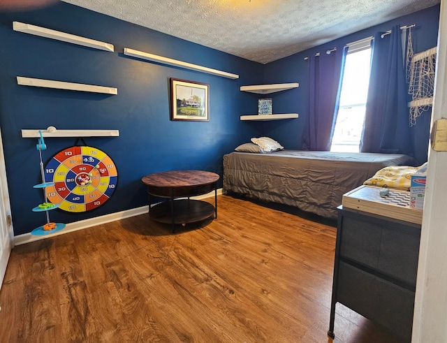 bedroom featuring a textured ceiling, baseboards, and wood finished floors