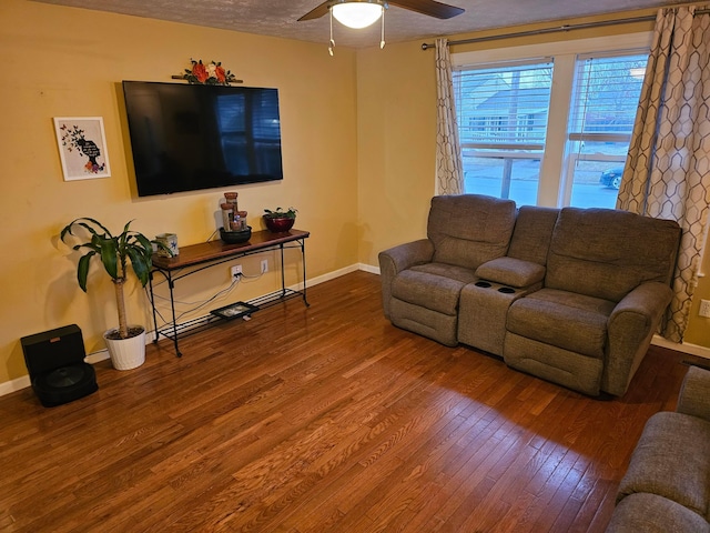 living area featuring a textured ceiling, a ceiling fan, baseboards, and wood finished floors