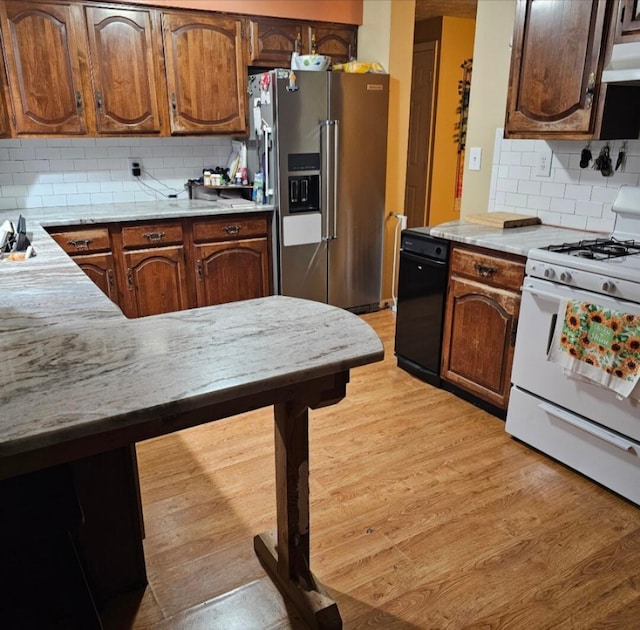 kitchen featuring under cabinet range hood, light countertops, white range with gas stovetop, high end refrigerator, and light wood-style floors