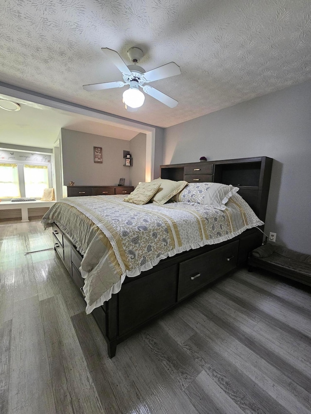 bedroom featuring a textured ceiling, wood finished floors, and ceiling fan