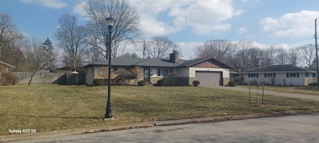 ranch-style house featuring concrete driveway, a chimney, an attached garage, fence, and a front lawn