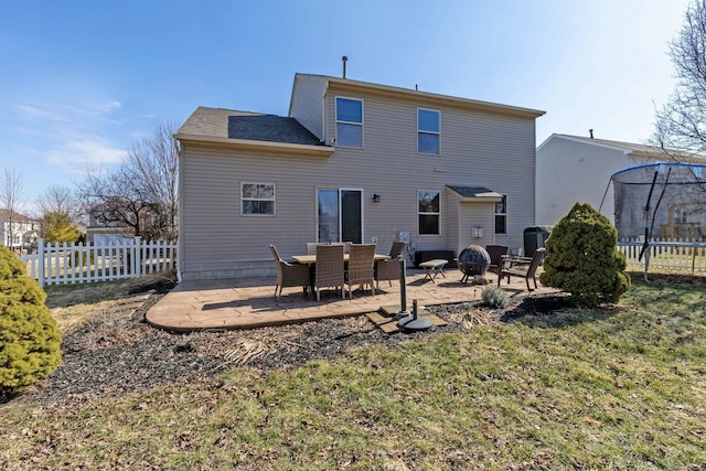 back of property with an outdoor fire pit, a patio, a trampoline, fence, and central AC