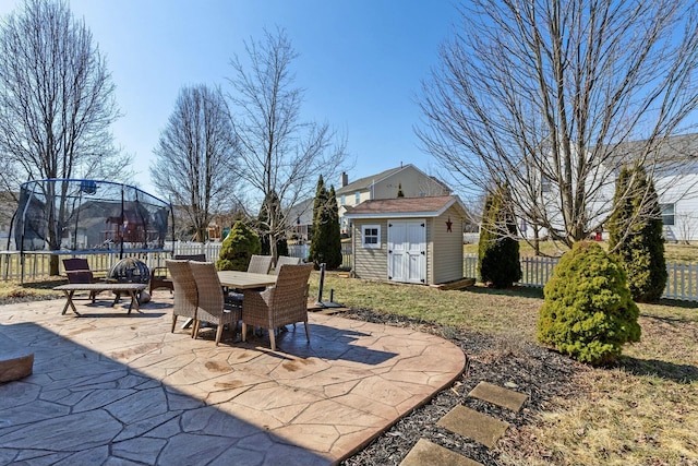 view of patio / terrace featuring outdoor dining area, an outdoor structure, fence, a shed, and a trampoline