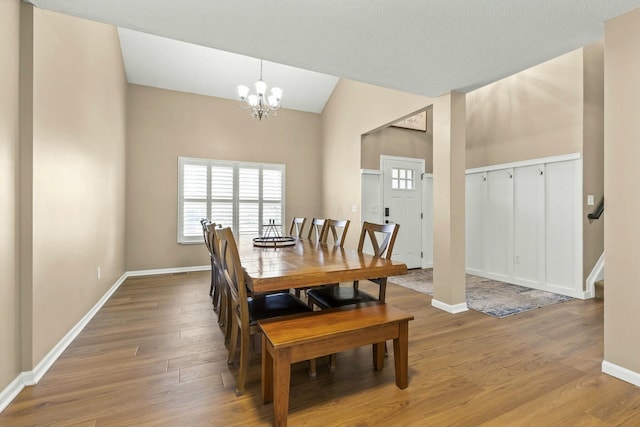 dining area featuring baseboards, lofted ceiling, stairway, wood finished floors, and a notable chandelier