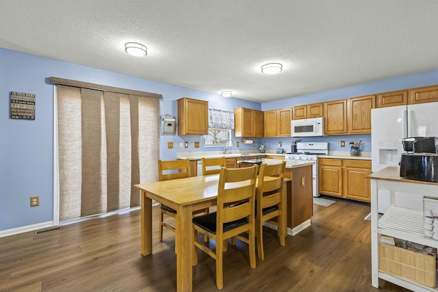 kitchen with white appliances, visible vents, dark wood-style floors, and light countertops