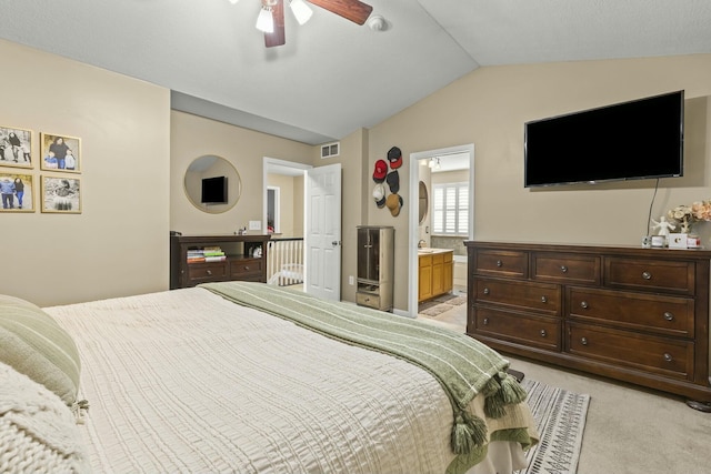 bedroom with light carpet, visible vents, lofted ceiling, ensuite bath, and ceiling fan